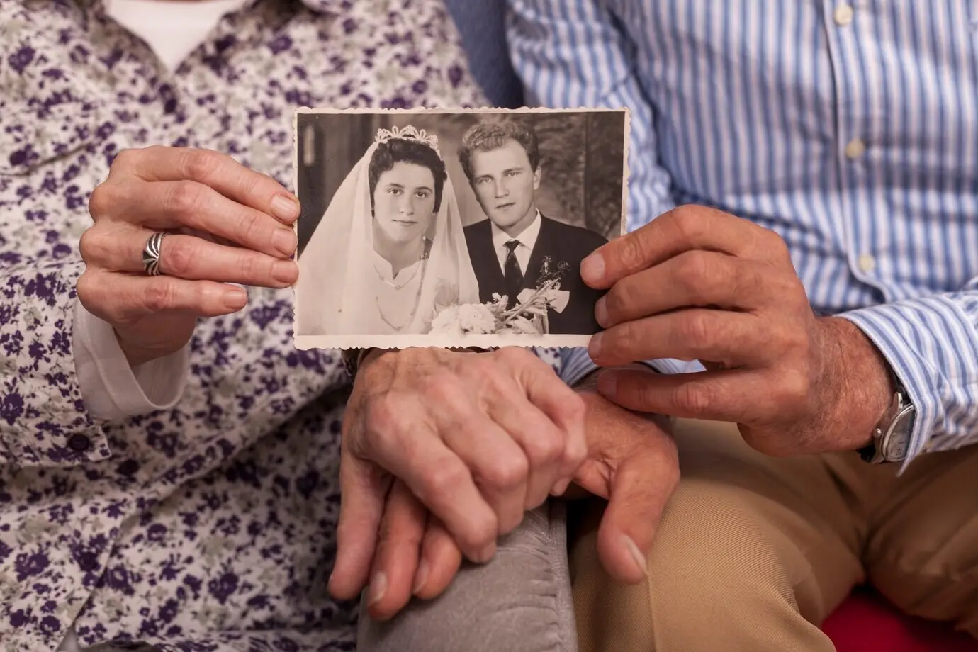 Primer plano de una pareja de ancianos sosteniendo una foto de boda.